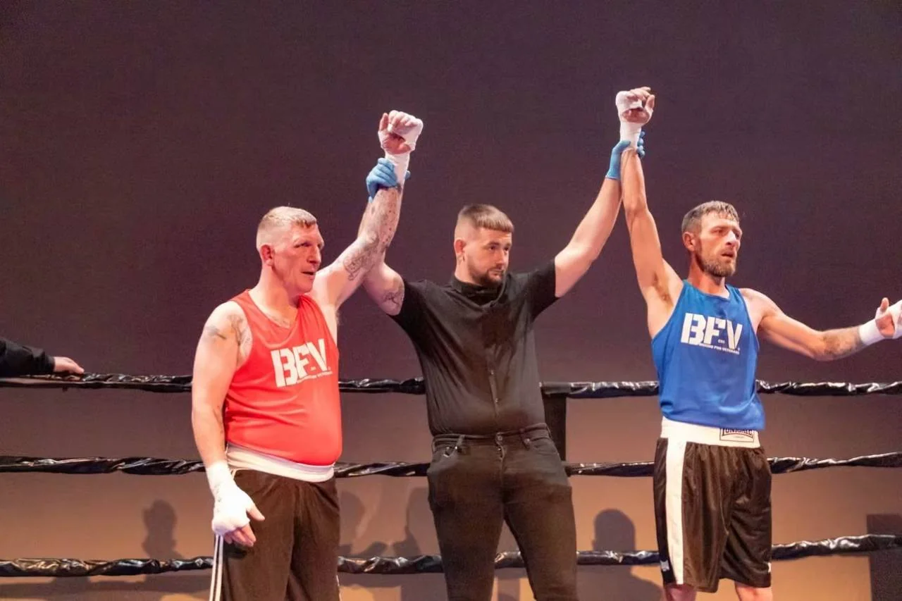 A referee raising the hands of two BFV boxers after their bout